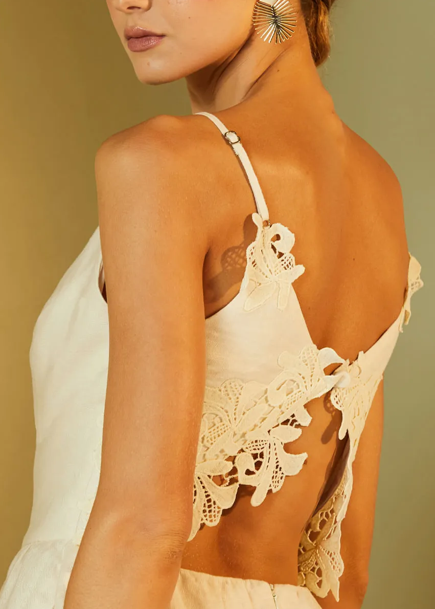 Woman wearing a beige lace backless dress against a beige background