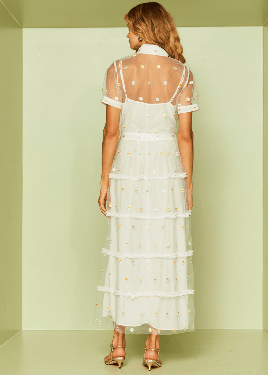 Woman wearing a white dress with sheer panels in a minimalistic setting