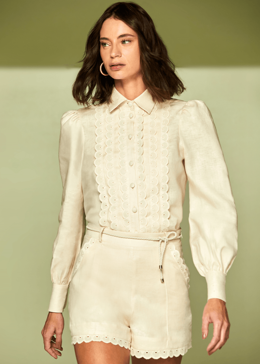 Woman wearing a cream-colored outfit with a matching top and shorts against a light green background
