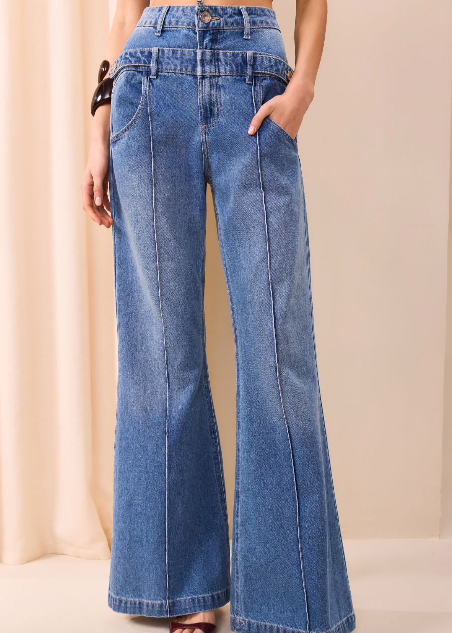 Person wearing high-waisted blue jeans against a beige background