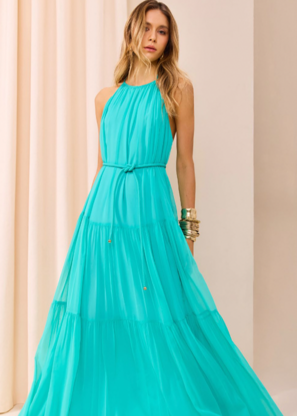 Woman wearing a turquoise dress against a beige curtain background