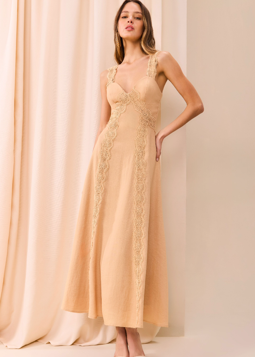 Woman wearing a beige lace dress against a beige curtain background