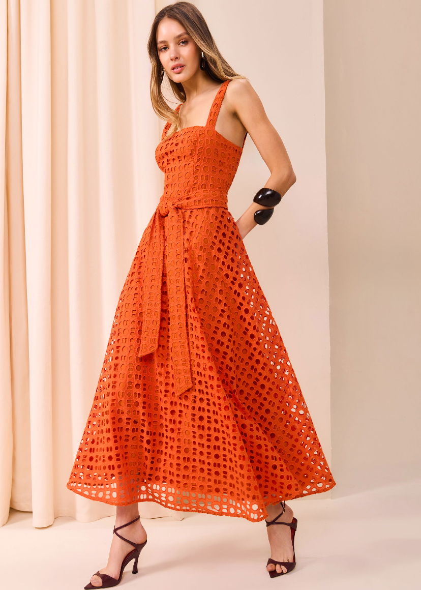 Woman wearing an orange dress with a beige curtain background