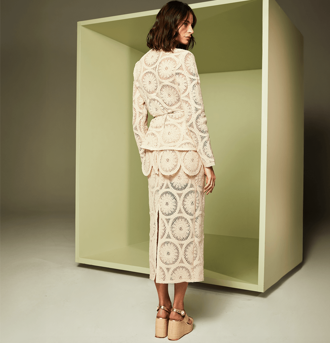 Woman wearing a white lace outfit standing inside a green box.