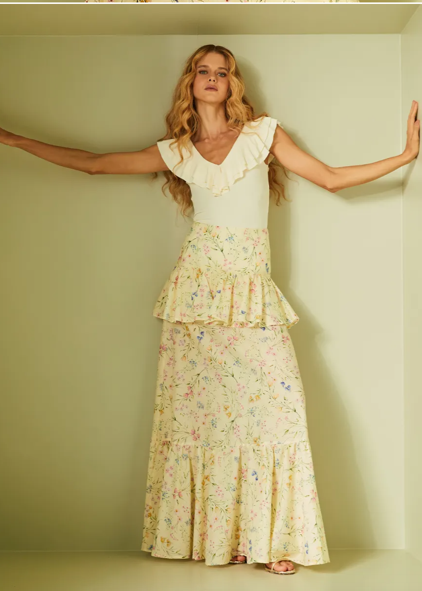 Woman wearing a floral dress standing in a minimalistic room.