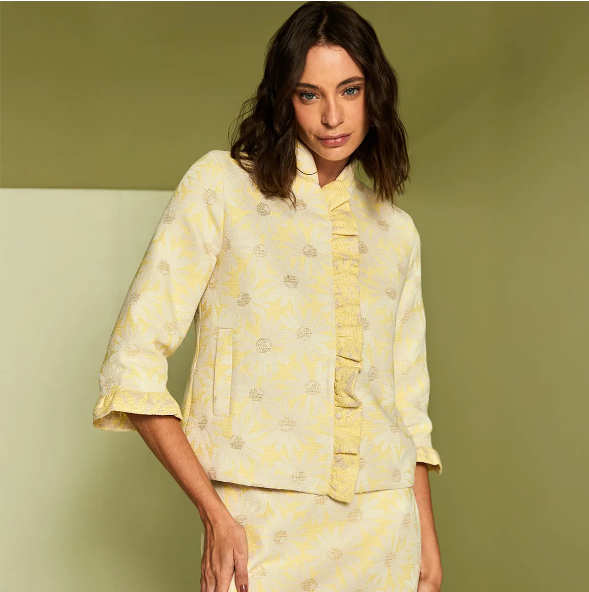 Woman wearing a yellow and white patterned outfit against a green background