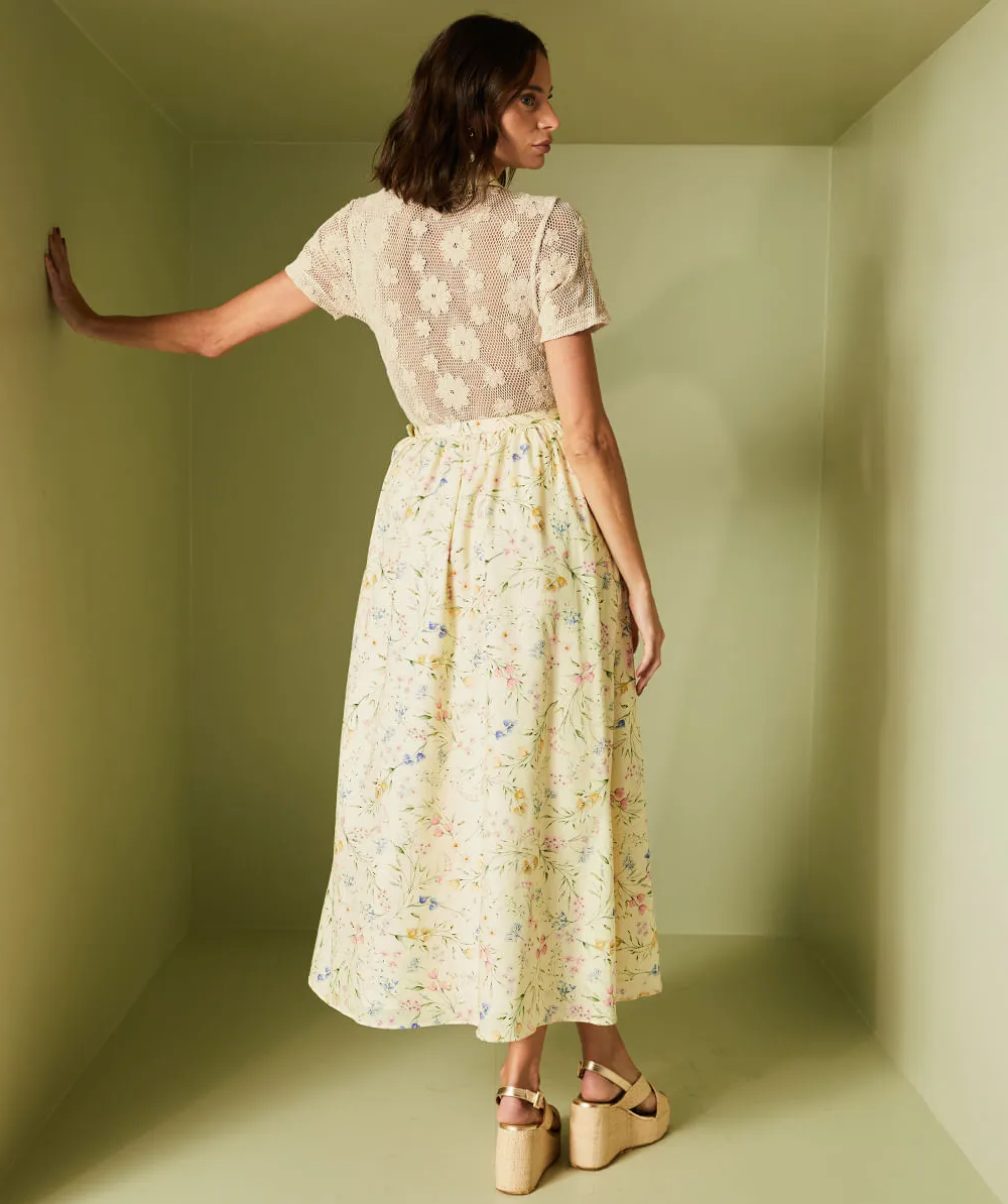 Woman wearing a floral dress standing in a room with green walls.