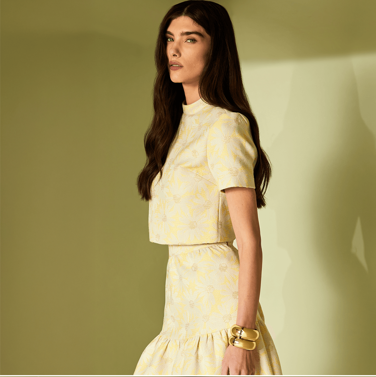 Woman wearing a yellow patterned outfit against a beige background
