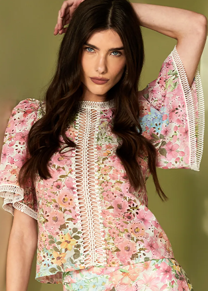 Woman wearing a pink floral dress with lace details against a beige background