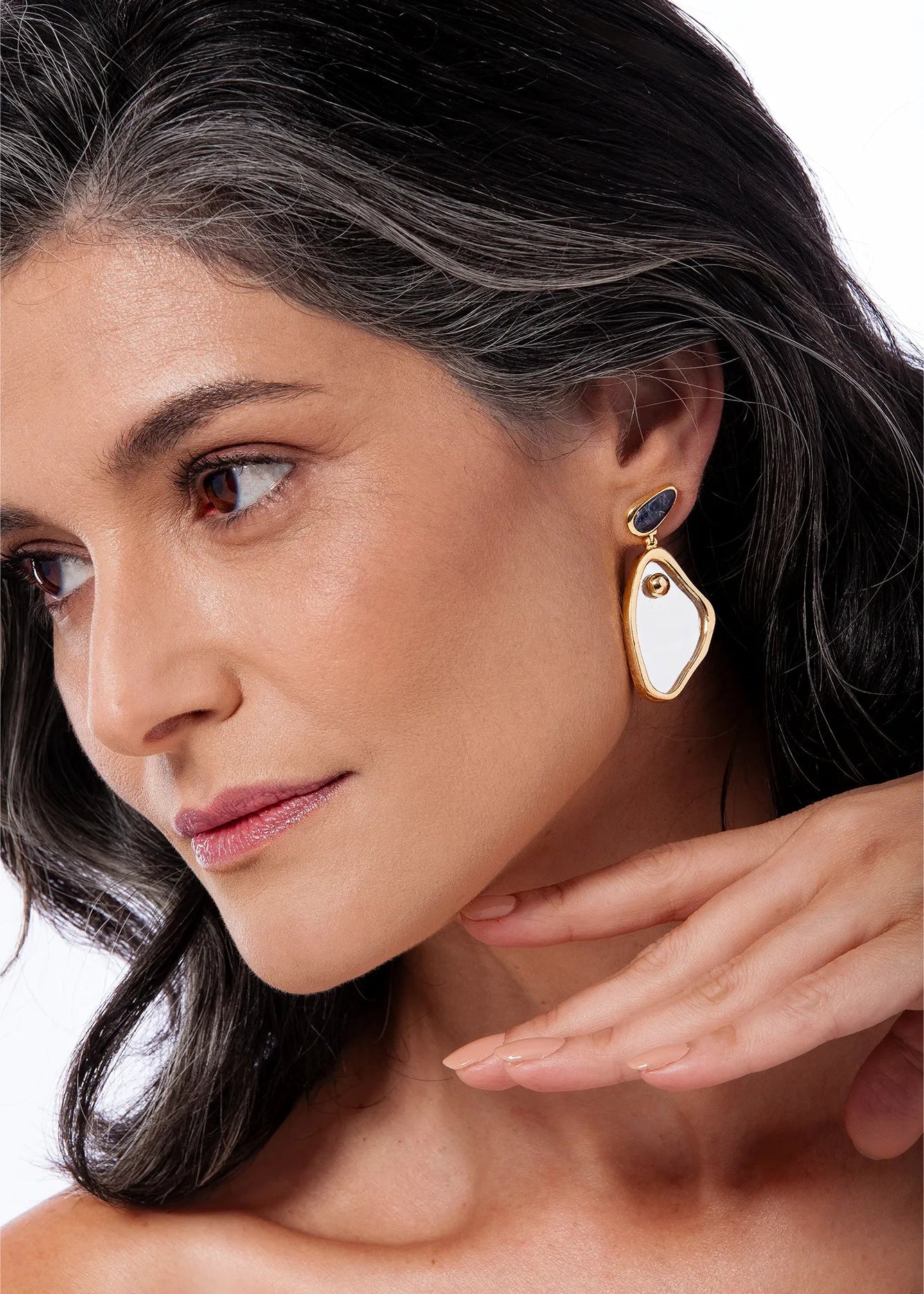 Close-up of a woman wearing gold earrings with a white background