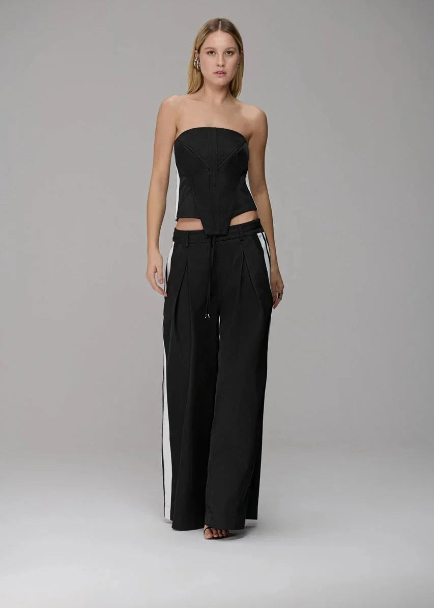 Woman wearing a black strapless top and wide-leg pants on a gray background