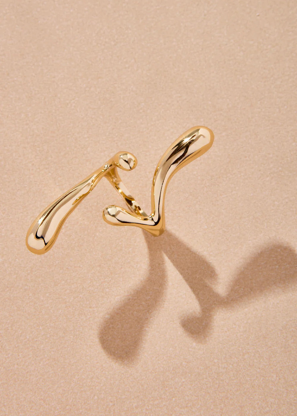 Gold earrings on a beige background