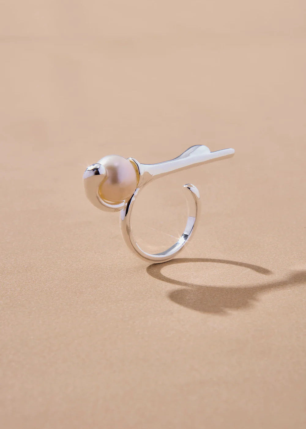 Silver ring with a pearl on a beige background