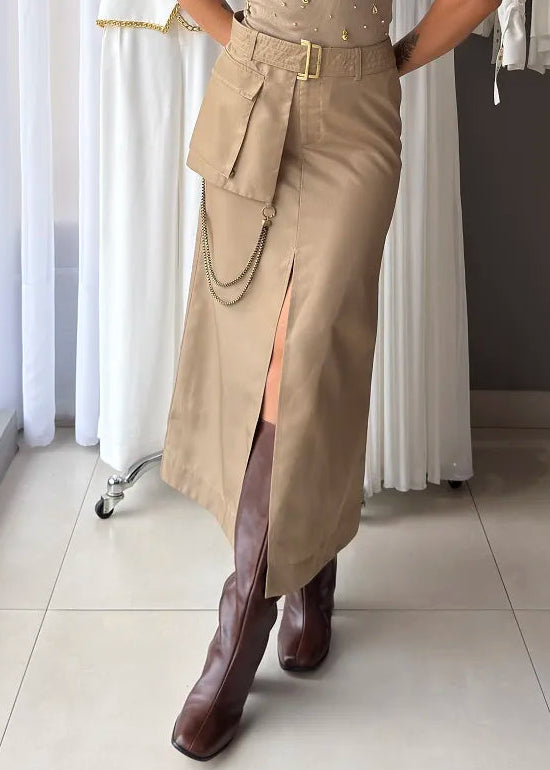 Woman in beige sleeveless top and skirt with brown boots standing in a clothing store.