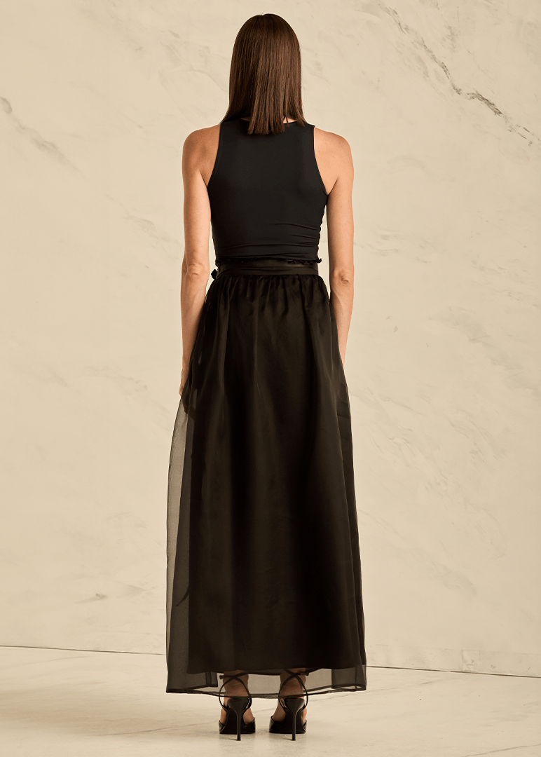 Woman wearing a black sleeveless top and long black skirt