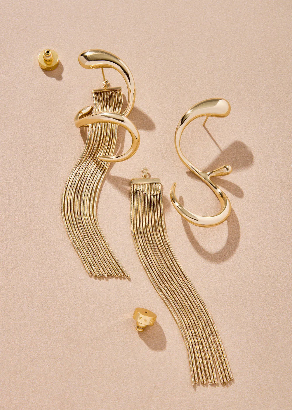 Gold earrings with fringe design on a beige background