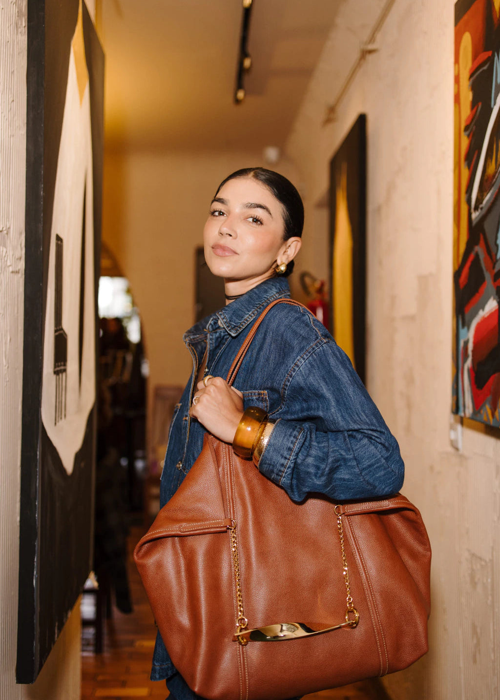 Woman holding a brown leather bag in an art gallery setting