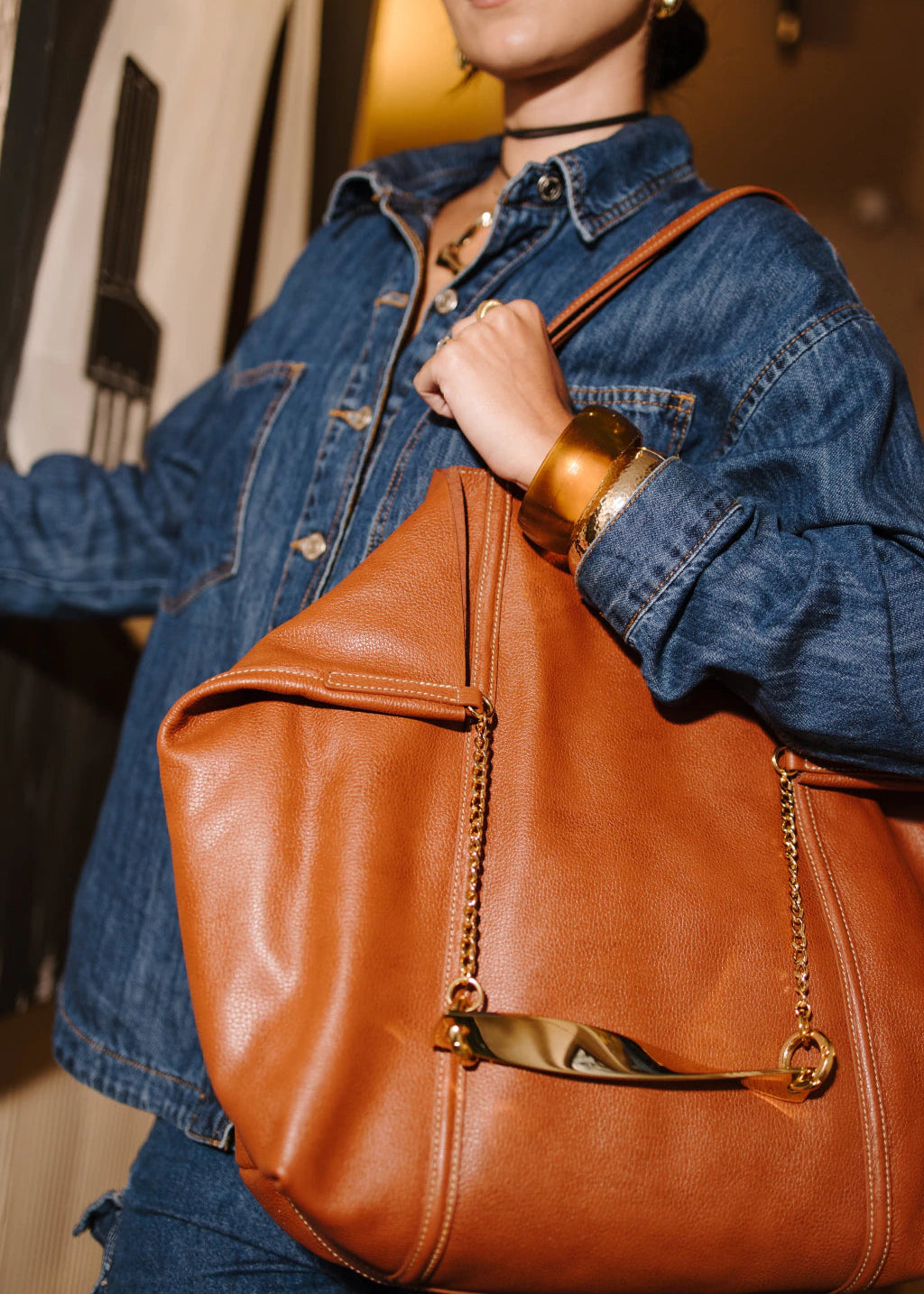 Person holding a brown leather handbag with a blurred background