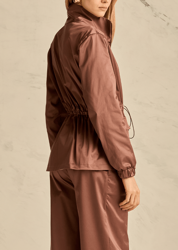 Person wearing a brown tracksuit against a beige background