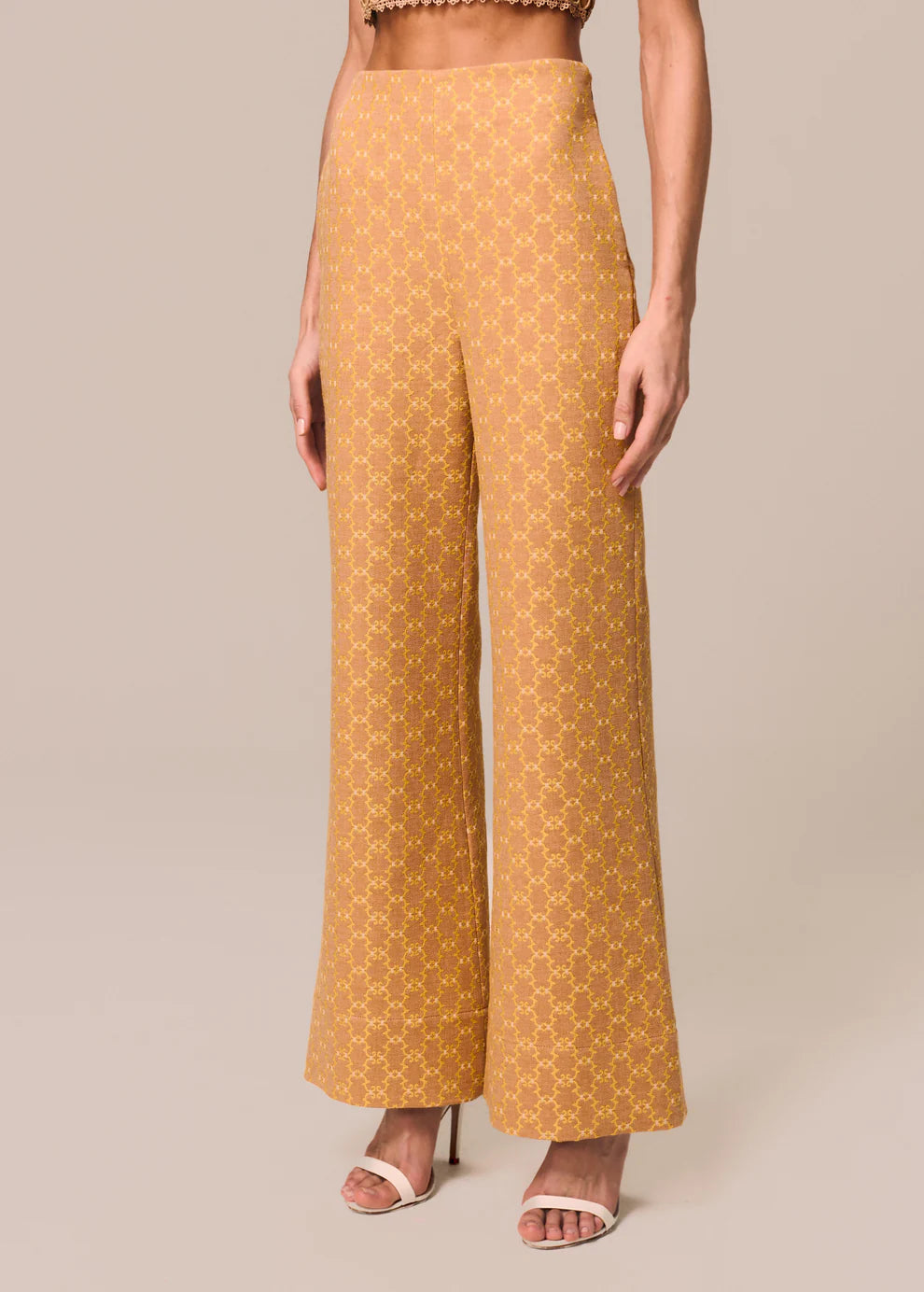 Mustard yellow patterned pants worn by a person on a beige background