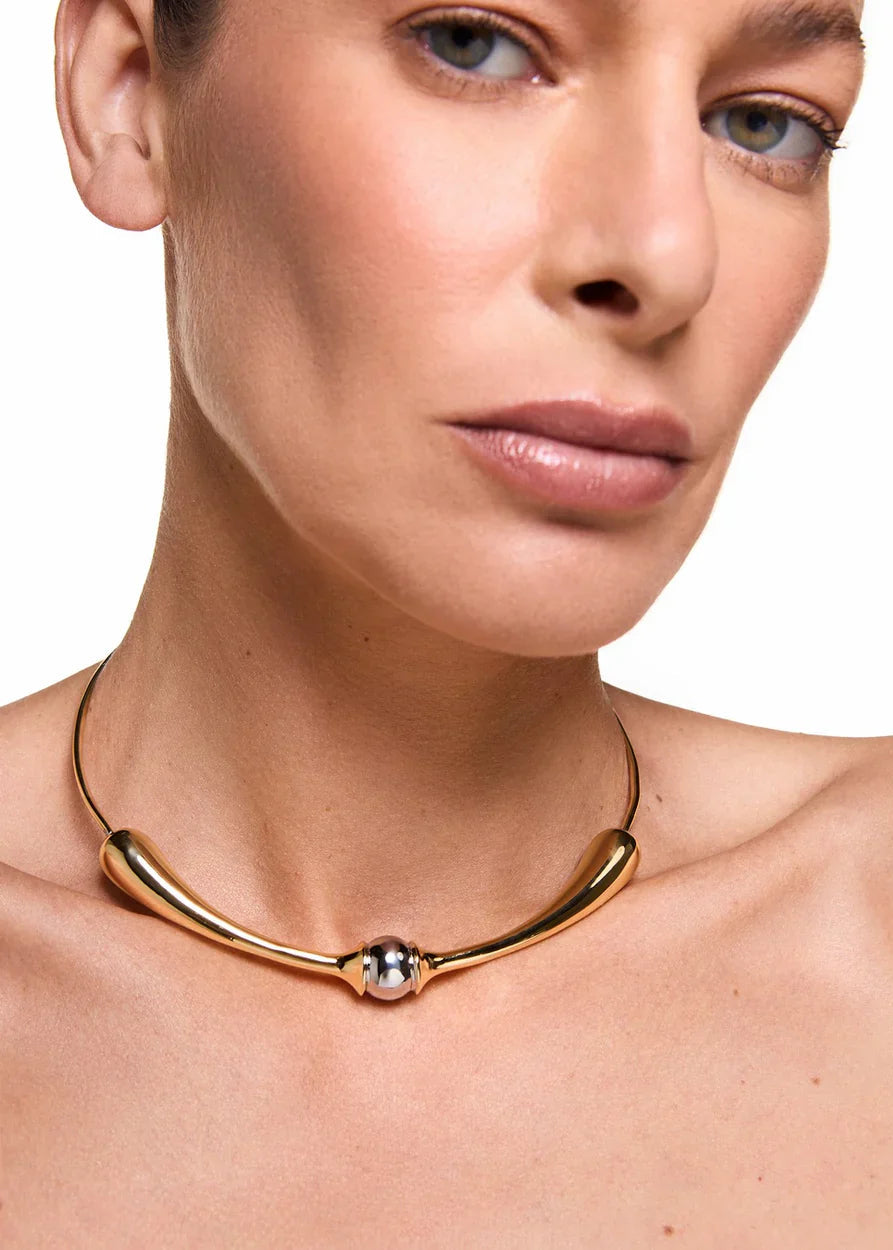 Gold necklace worn by a person on a white background