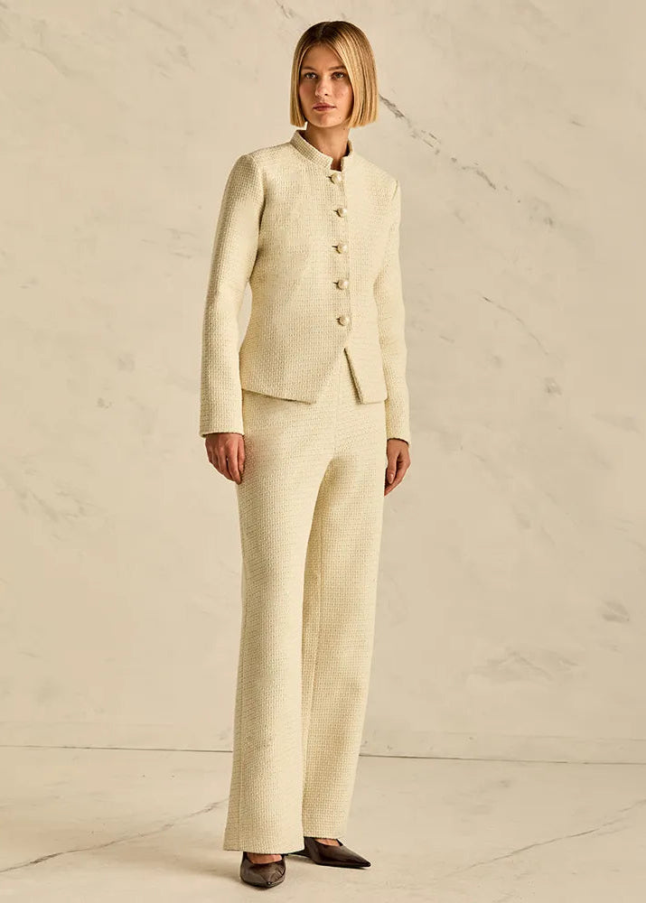 Woman wearing a beige suit standing against a plain background