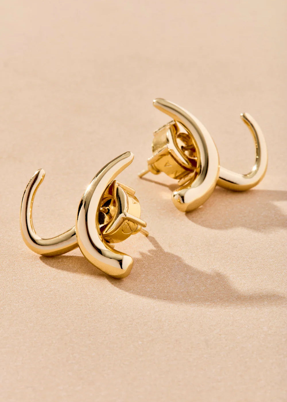 Gold crescent moon earrings on a beige background
