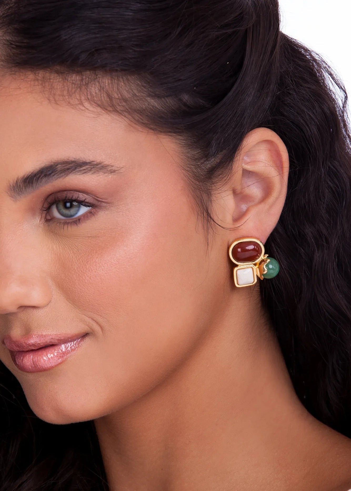 Close-up of a woman wearing a colorful earring with a neutral background