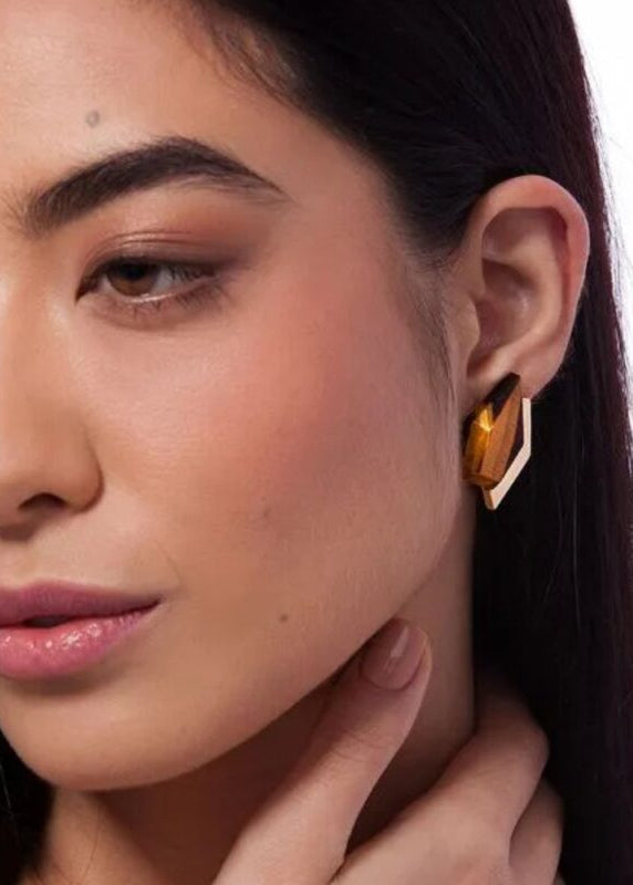 Close-up of a woman wearing a gold earring with a white background