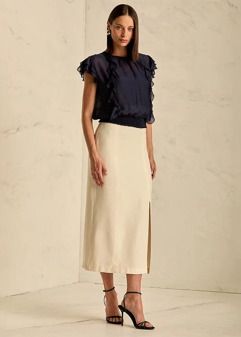 Woman wearing a black ruffled blouse and beige skirt