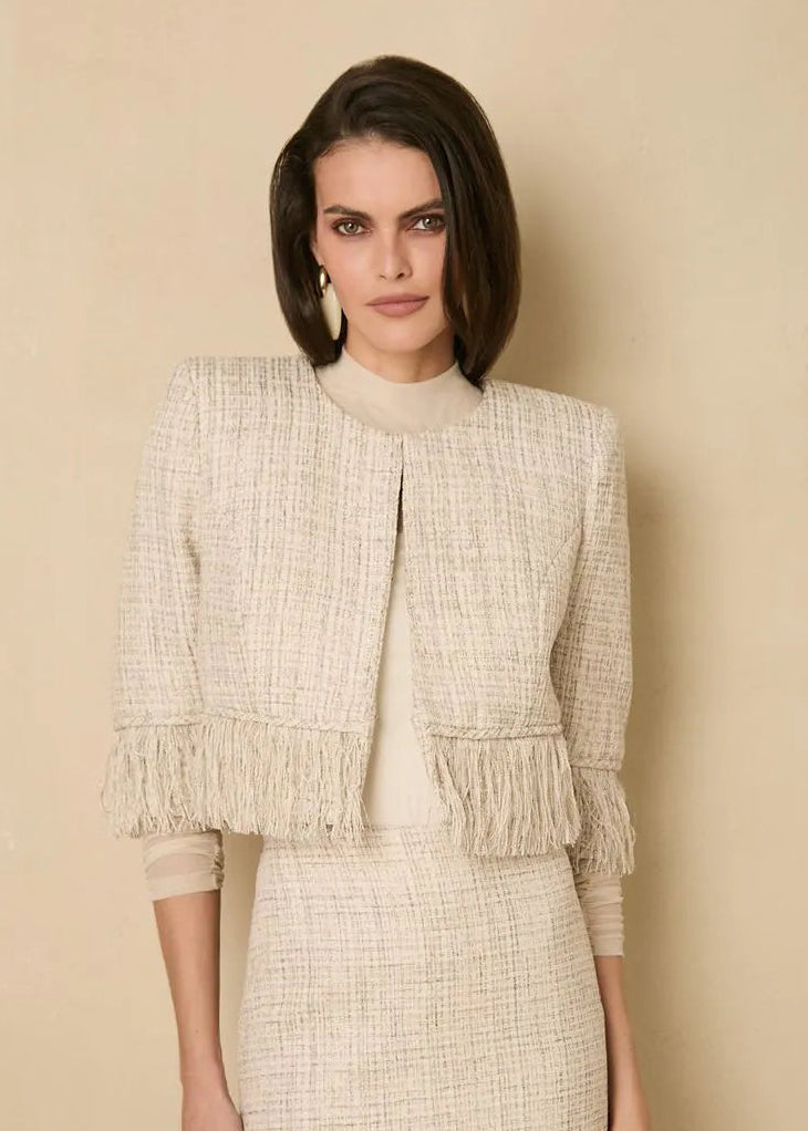 Woman wearing a beige tweed outfit against a beige background
