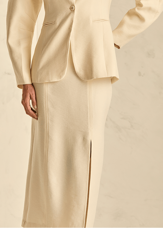 Woman wearing an off white midi skirt and a beige suit