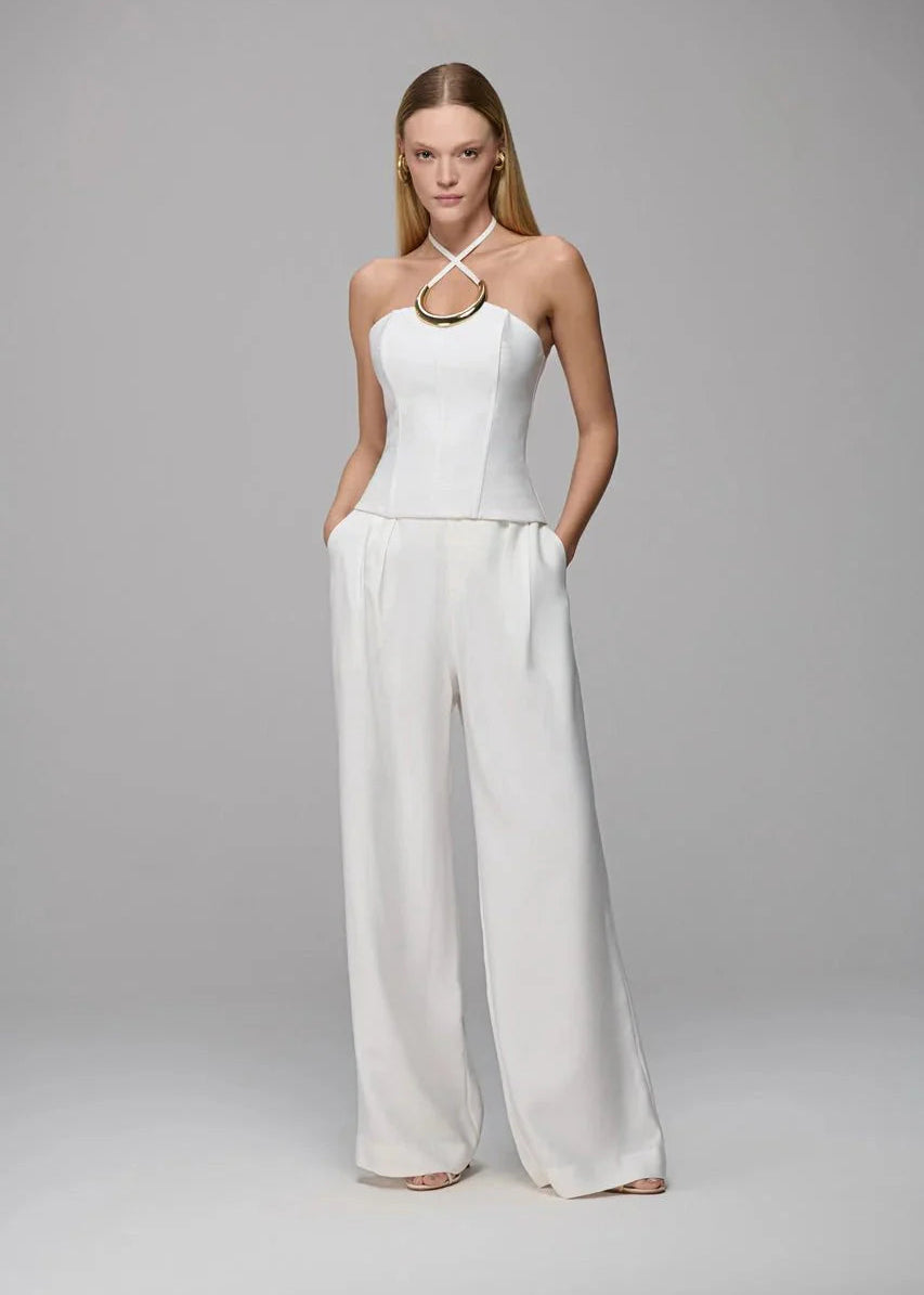 Woman wearing a white halter top and wide-leg pants on a gray background