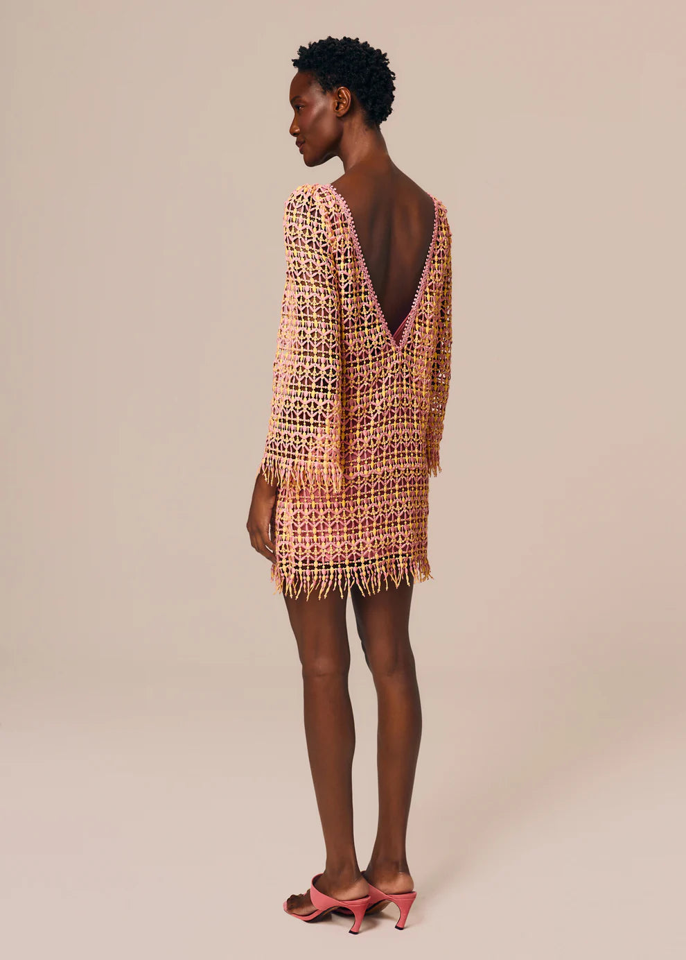 Woman wearing a patterned dress with open back on a beige background