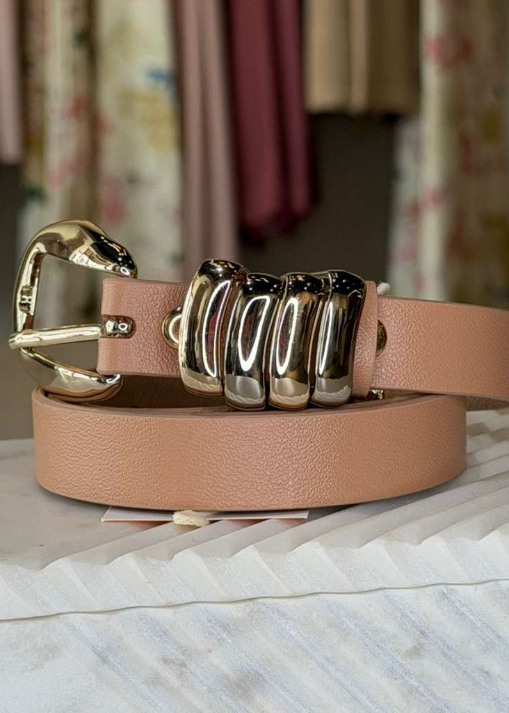 peach color belt with gold and silver knuckle-style buckle on a marble surface.