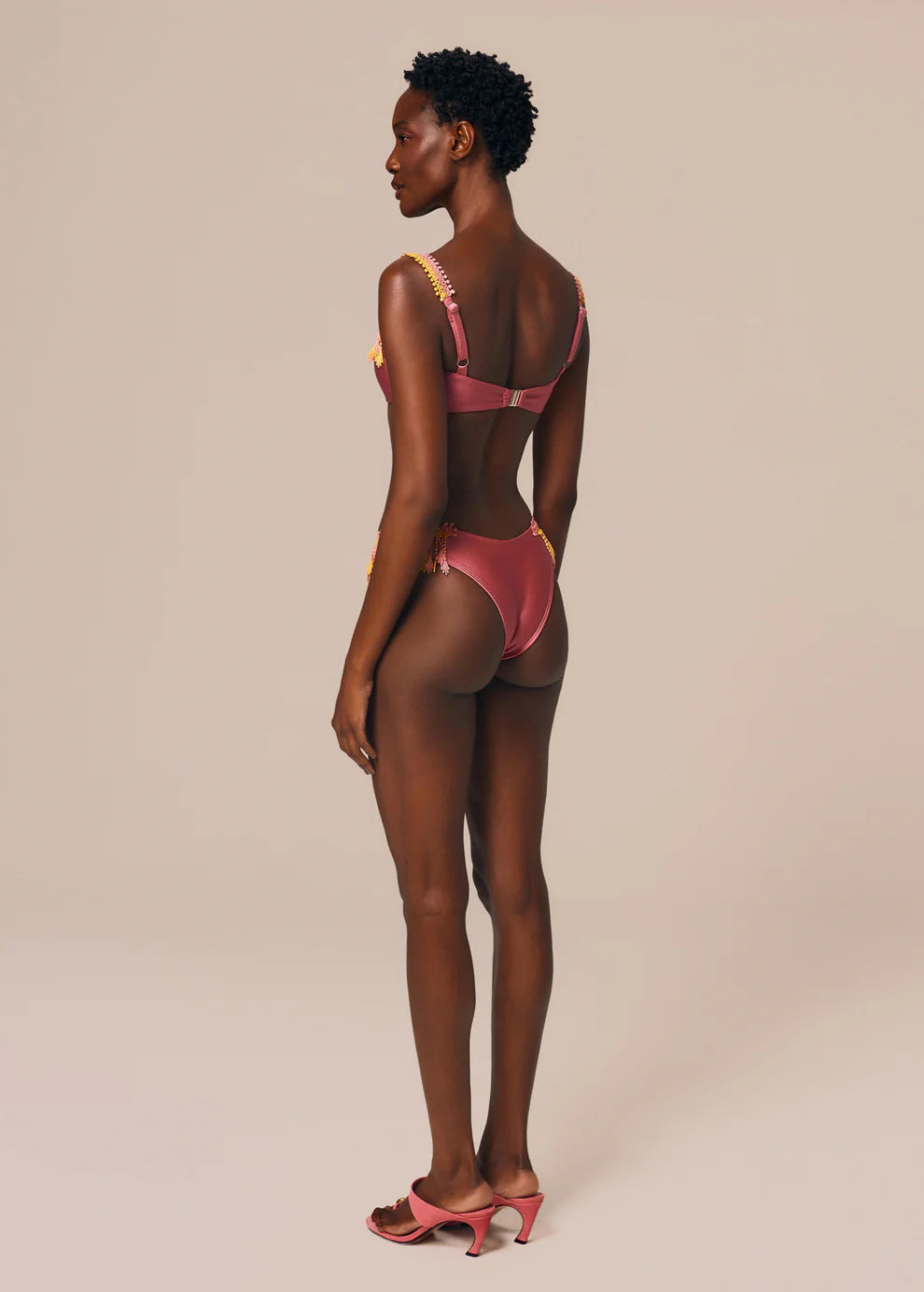 Woman wearing a pink bikini against a beige background
