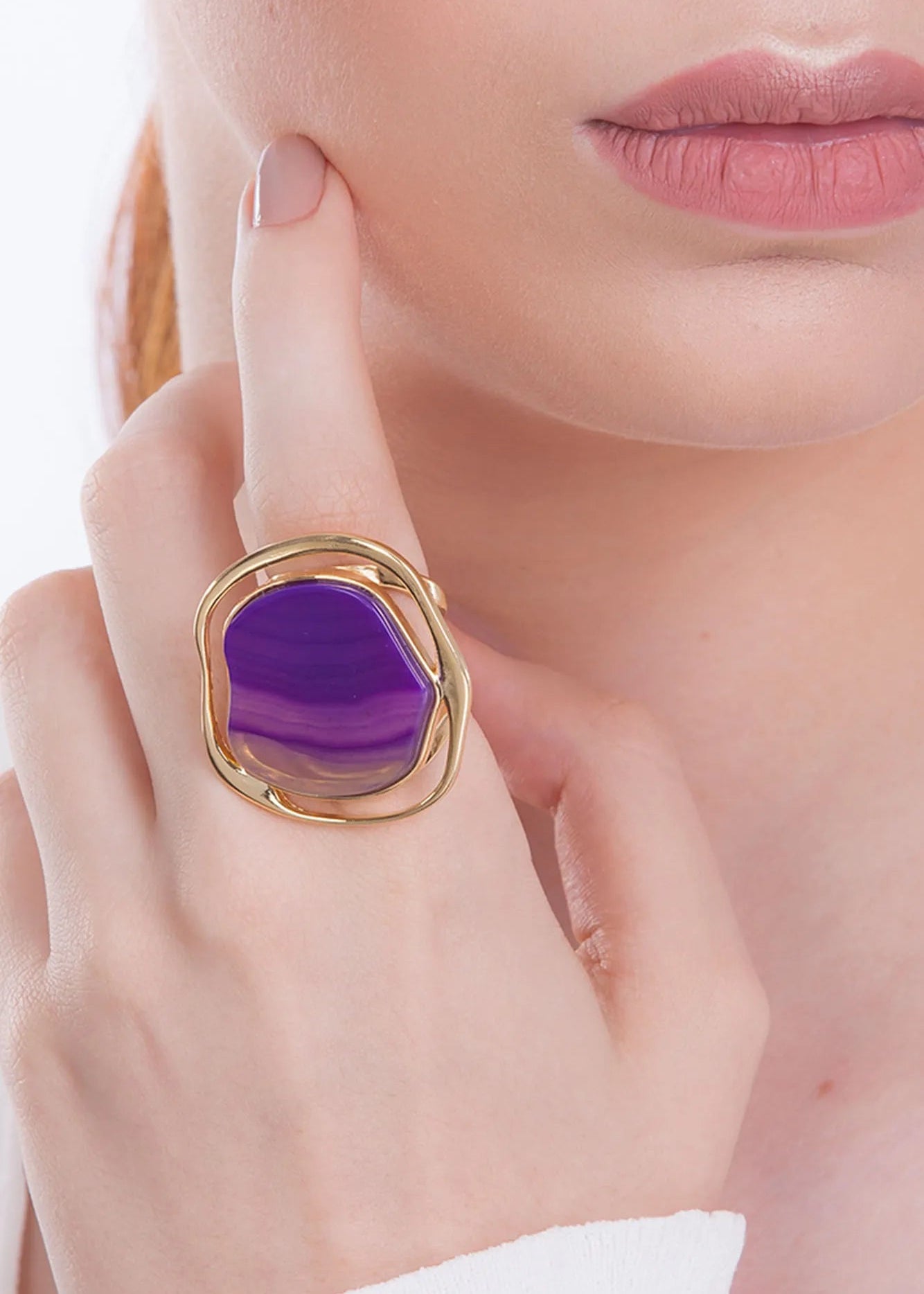 Close-up of a hand wearing a gold ring with a purple gemstone.