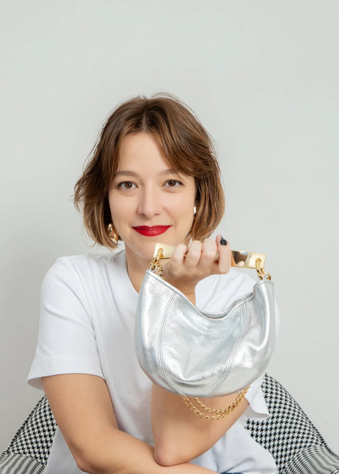 Woman holding a gold handbag with a plain background