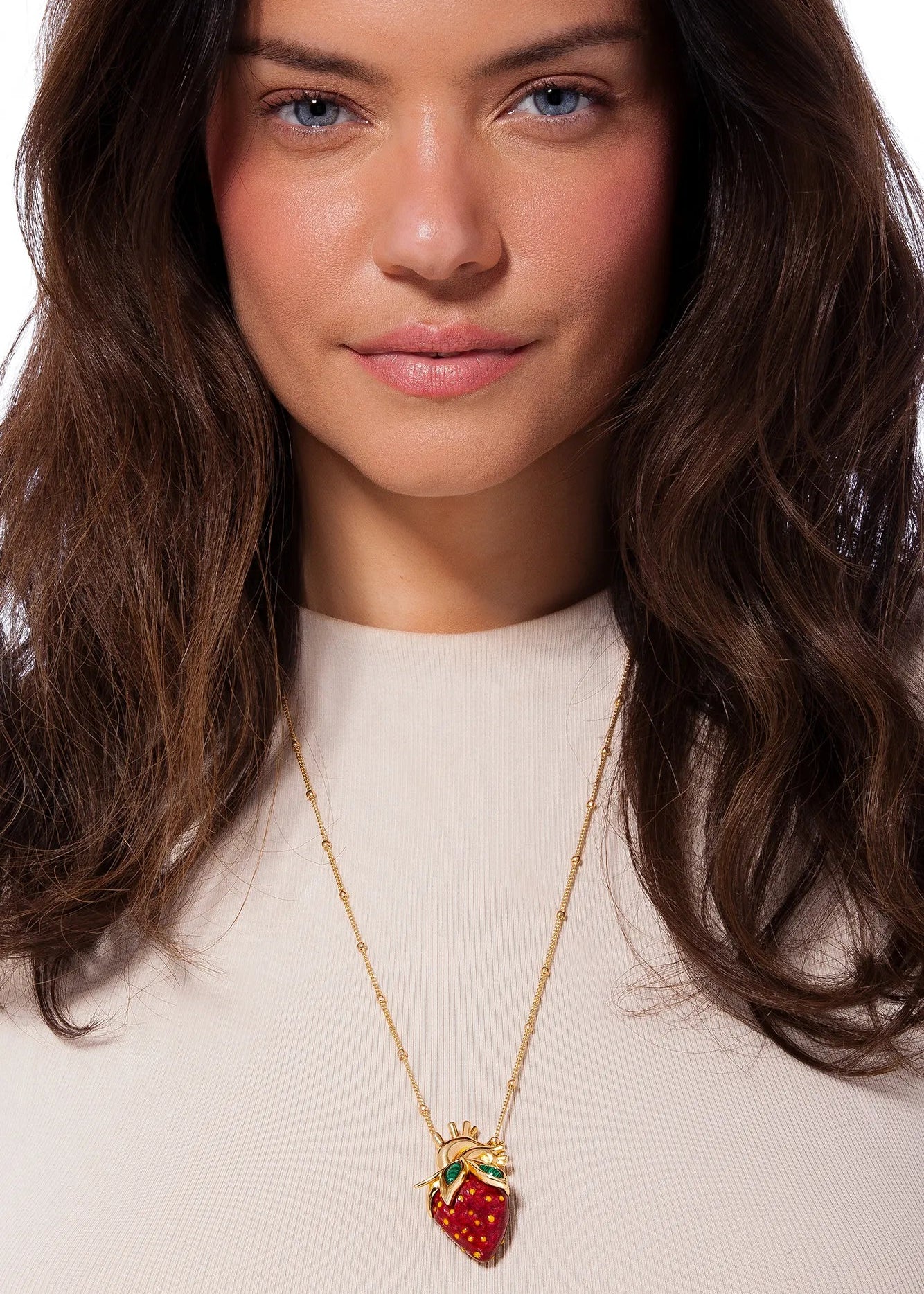 Woman wearing a strawberry pendant necklace on a white background