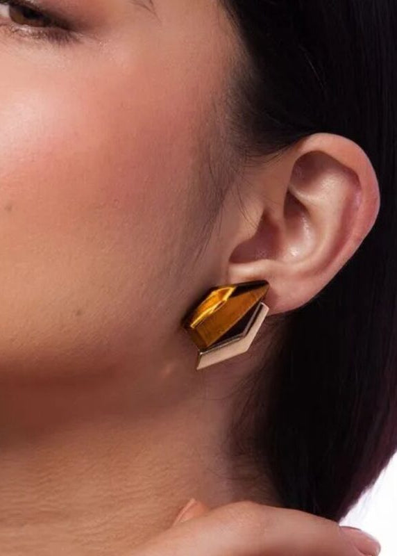 Close-up of a person wearing a gold geometric earring.