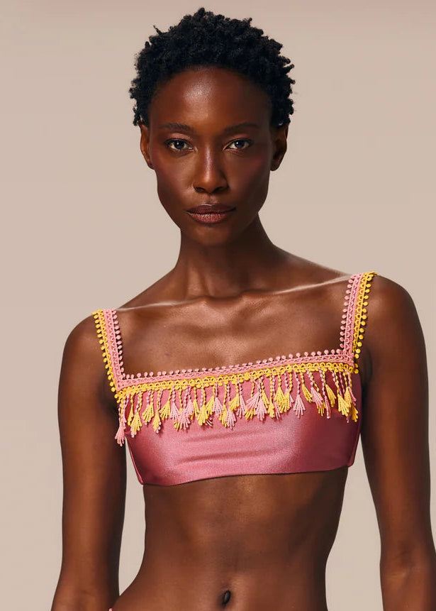 Woman wearing a pink bikini with yellow accents against a beige background