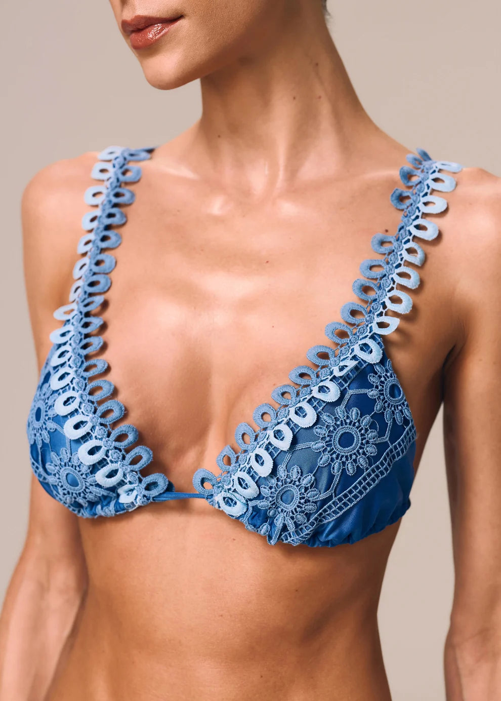 Blue lace bikini top worn by a model on a neutral background