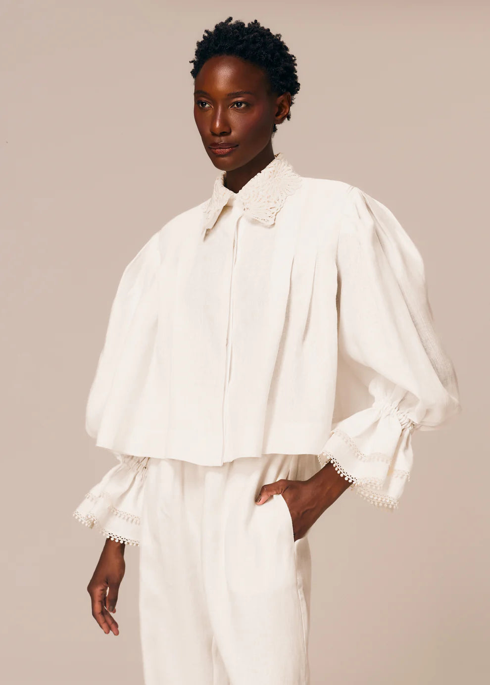 Woman wearing a white blouse with puffed sleeves on a beige background