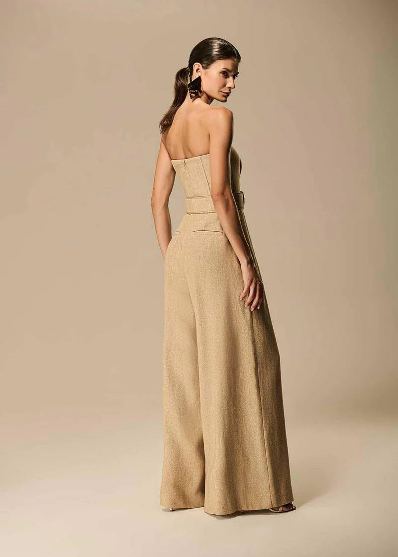 Woman wearing a beige strapless jumpsuit against a beige background