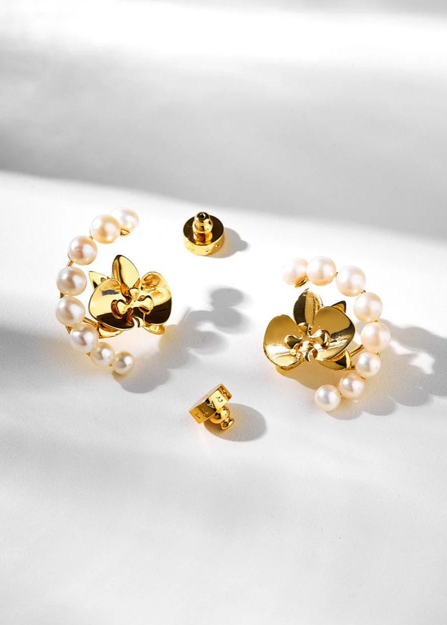 Gold floral earrings with pearl accents on a light background