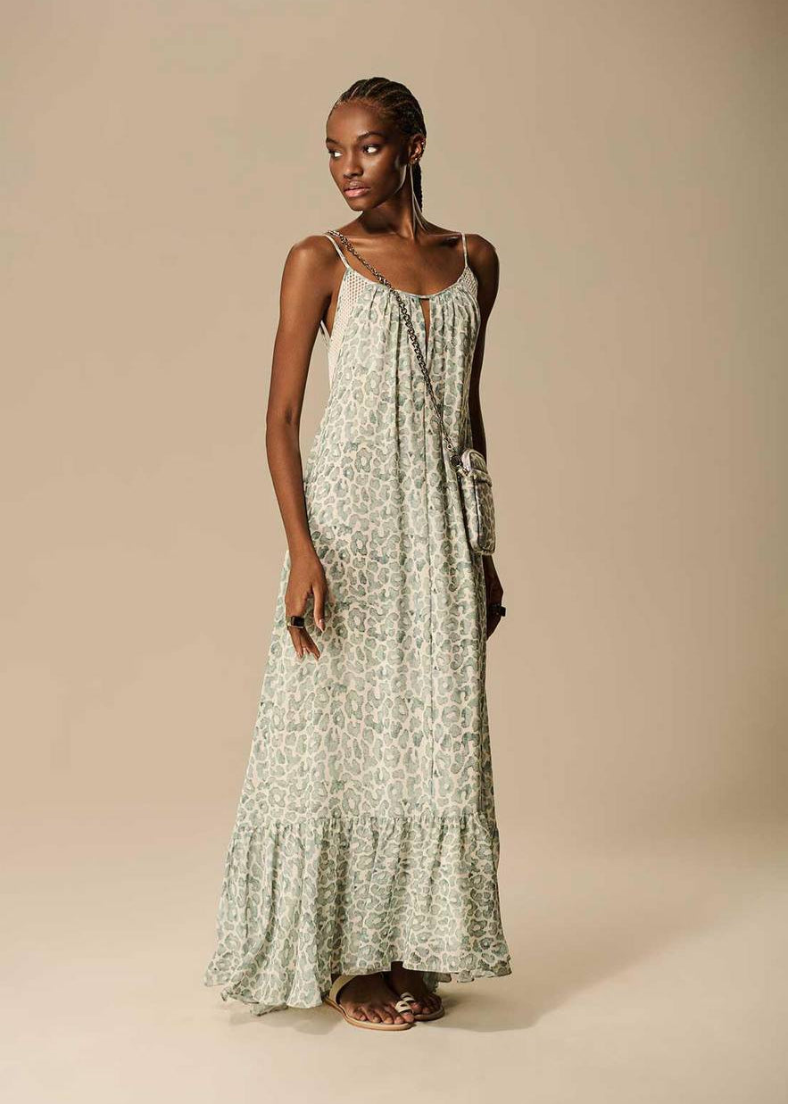 Woman wearing a long, light-colored floral dress against a beige background