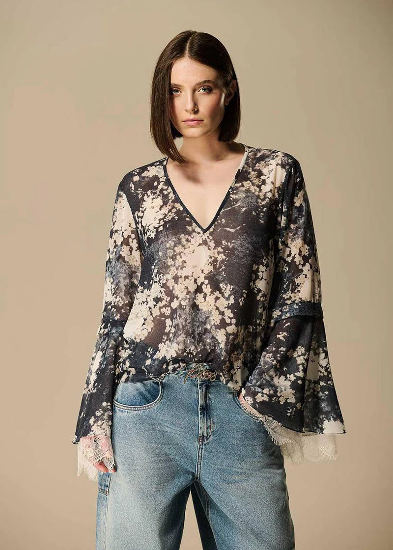 Woman wearing a floral blouse and jeans against a beige background