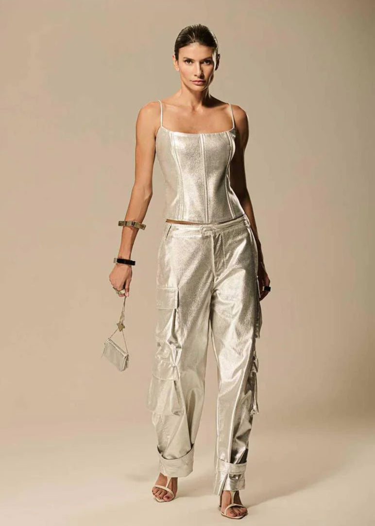Woman wearing a silver jumpsuit against a beige background