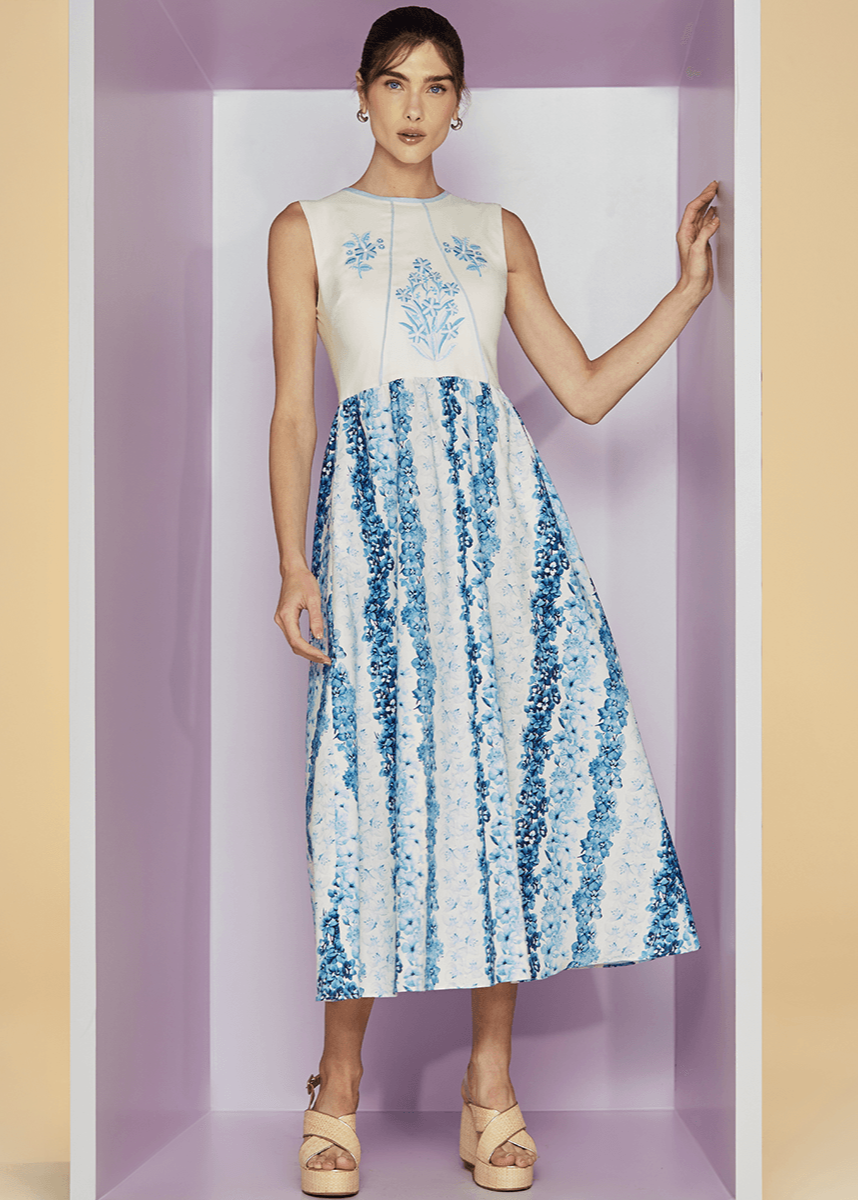 Woman wearing a sleeveless dress with floral patterns against a pastel background