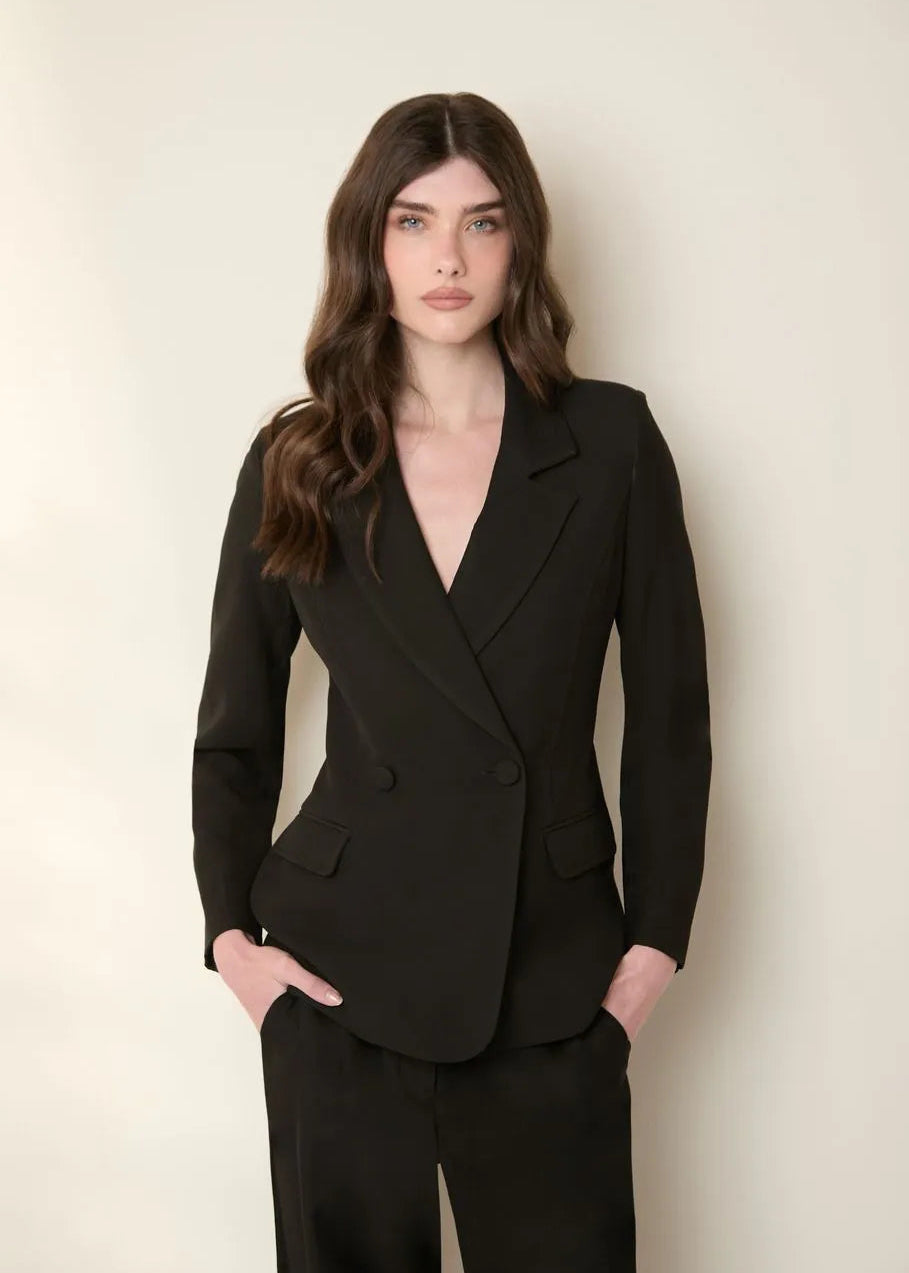 Woman wearing a black suit against a plain background